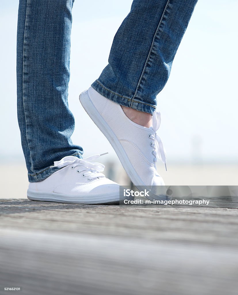 Woman legs in comfortable white shoes standing outdoors Pair of woman legs in comfortable white shoes standing outdoors Active Lifestyle Stock Photo
