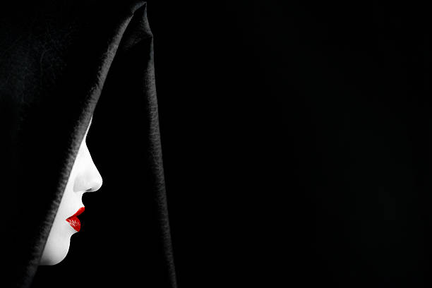 a mysterious woman wearing a black cape covering her white face