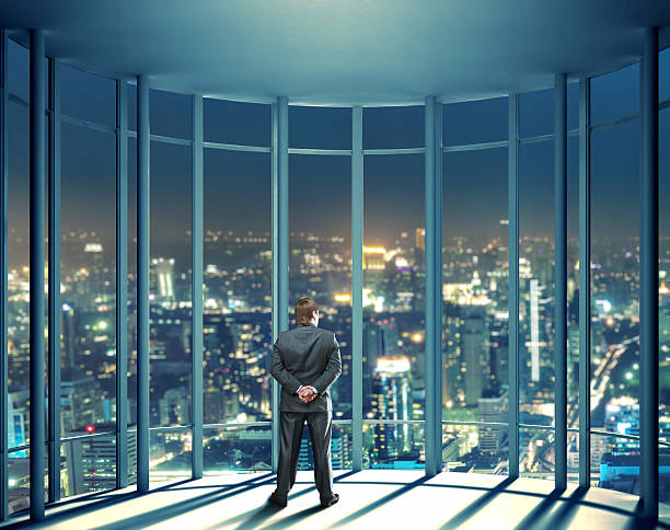 istock Night view of buildings and man from glass window 521668065