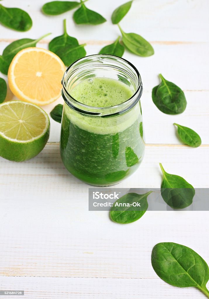 Green spinach smoothie Glass jar of fresh summery drink green smoothie, spinach leaves, lime fruit. Vertical. Blended Drink Stock Photo