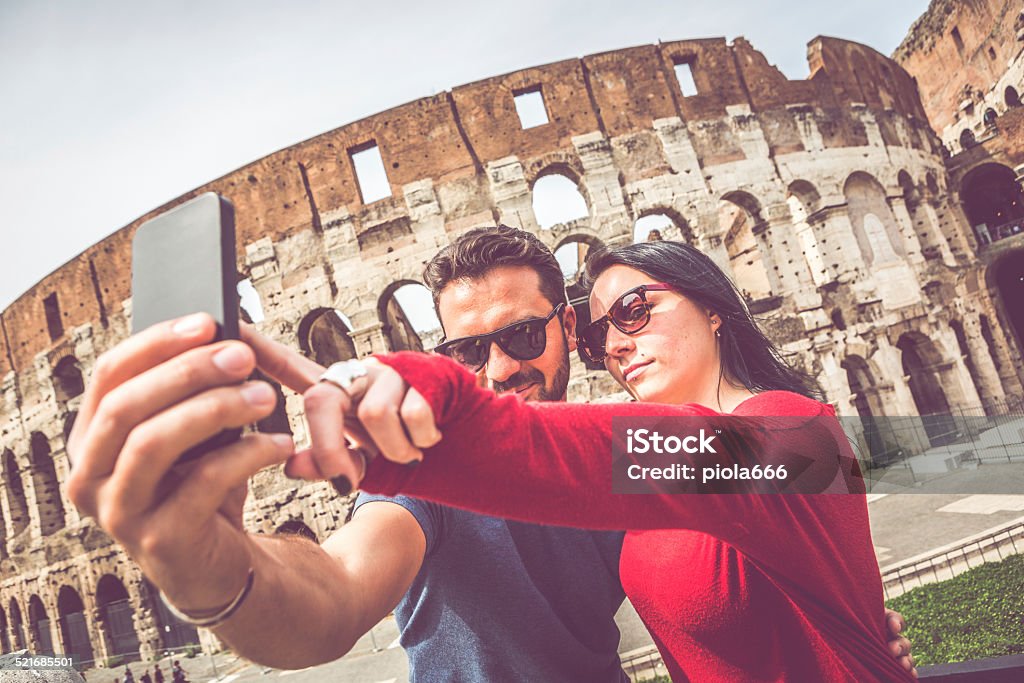 Tourist couple taking a selfie in front of the Coliseum Couple taking a selfie in front of the Coliseum, Rome Rome - Italy Stock Photo