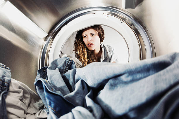 istock Pretty woman pulling face at laundry in drier 521686663