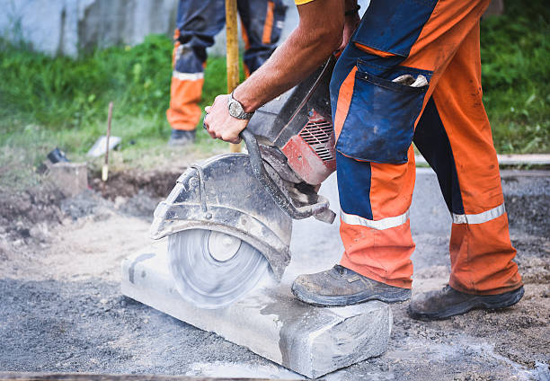 Construction worker cutting concrete paving stabs or metal for s Construction worker cutting concrete paving stabs or metal for sidewalk using a cut-off saw. Profile on the blade of an asphalt or concrete cutter with workers shoes and protective gear. razor blade photos stock pictures, royalty-free photos & images