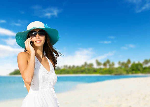 istock Young woman with mobile phone on a beach 521688832