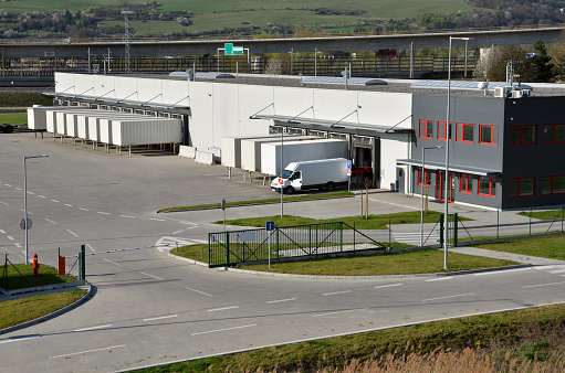 Modern logistics center, white van and trailers standingon ramp