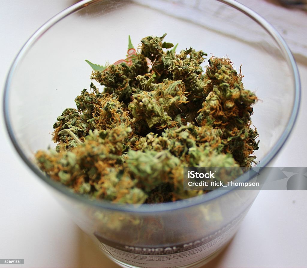 Medical Marijuana in a Glass Medical Marijuana is weighed out and ready to be placed in a child-proof container for transportation home by a registered patient. This photo was taken in Michigan. The buds are dry and the characteristic orange hairs and sticky trichomes are visible.  Alternative Medicine Stock Photo
