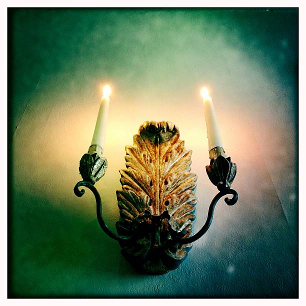 Burning candles on an old wooden carved wall chandelier. Shot with an iPhone.