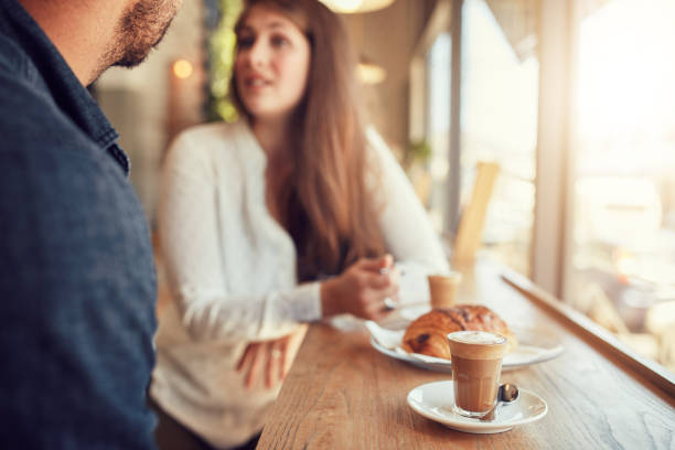 istock Cup of coffee and food on table with couple talking 521692974