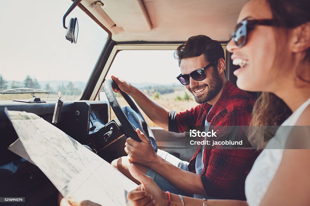 Happy young couple with a map in the car Happy young couple with a map in the car. Smiling man and woman using map on roadtrip. Car Stock Photo