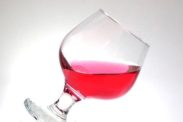 A wineglass with red water in white background.