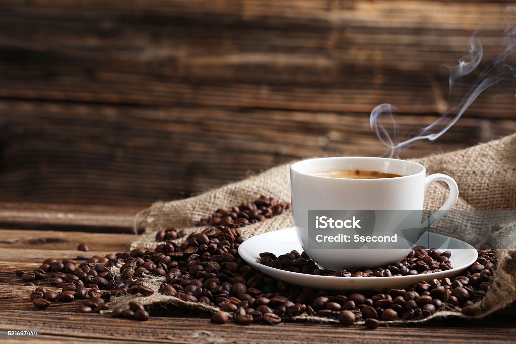 Cup of coffee with coffee beans Cup of coffee with coffee beans on a brown wooden background Coffee - Drink Stock Photo