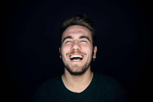 Portrait of smiling young man on black background.
