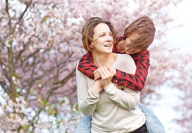 istock Mother and daughter hugging in blossoming cherry tree orchard 521698988