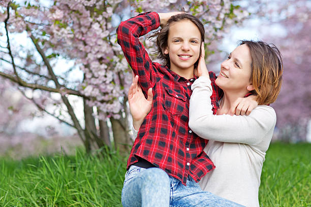 istock Mother and daughter hugging in blossoming cherry tree orchard 521699098
