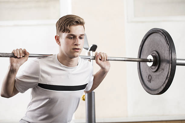 młodzieżowe zaangażowany w sport ćwiczenia przy użyciu sztanga. - gym health club school gymnasium exercising zdjęcia i obrazy z banku zdjęć