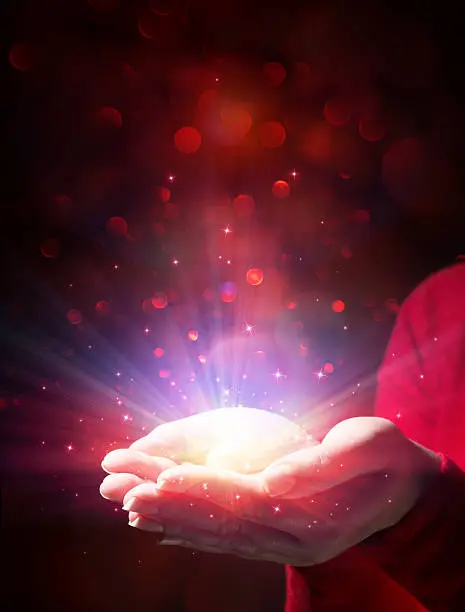 giving light and magic - woman hands and sparkle red background