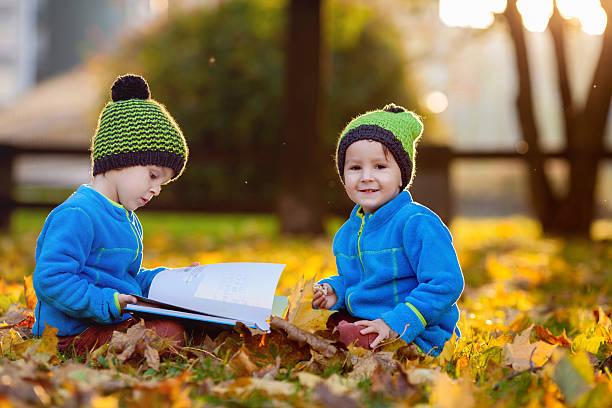 istock Two boys, reading a book on lawn in the afternoon 521700715