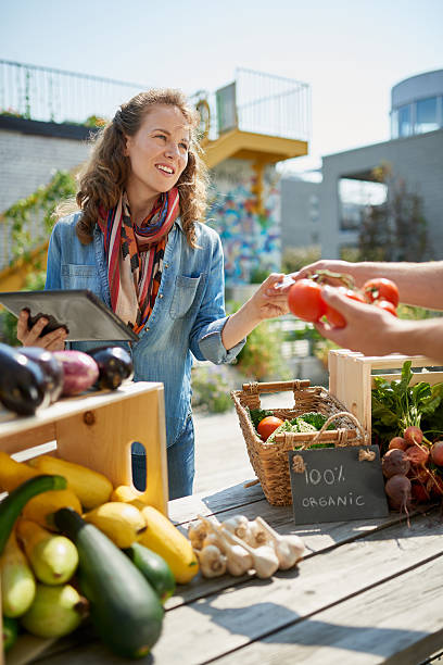 istock Friendly woman tending an organic vegetable stall at a farmer 521702486