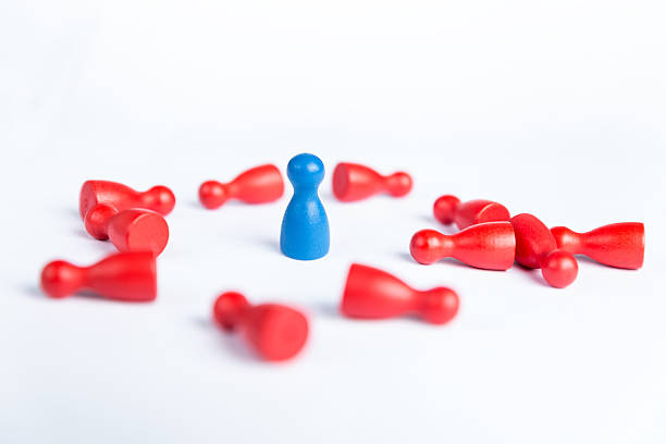 istock Blue figurine surrounded by red pawns lying on the floor 521703719