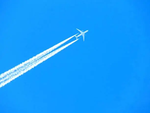 Airplane with chemtrails on blue sky