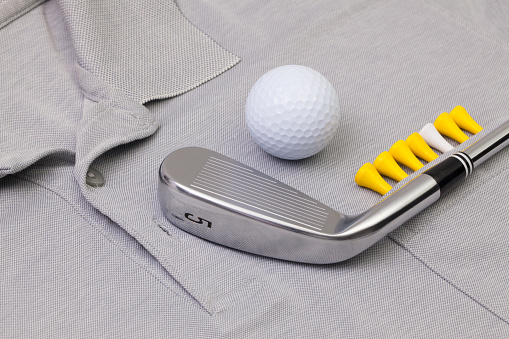 Detail of grey polo shirt and golf equipments