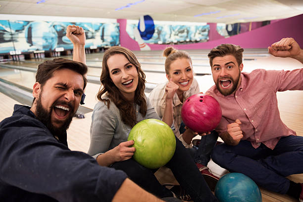 besten freunde verbringen zeit am bowling - bowling holding bowling ball hobbies stock-fotos und bilder