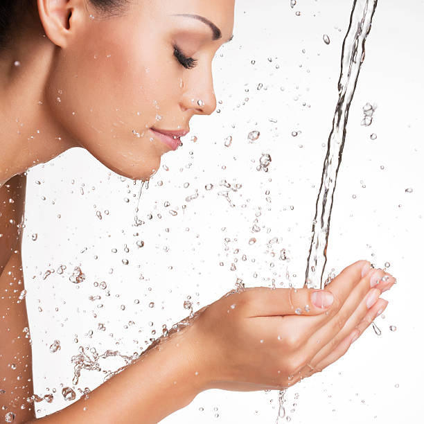 Closeup portrait of a beautiful woman washing her clean face with water  