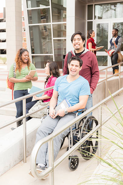 istock Education: Disabled student helped down wheelchair ramp. College campus. 521706982