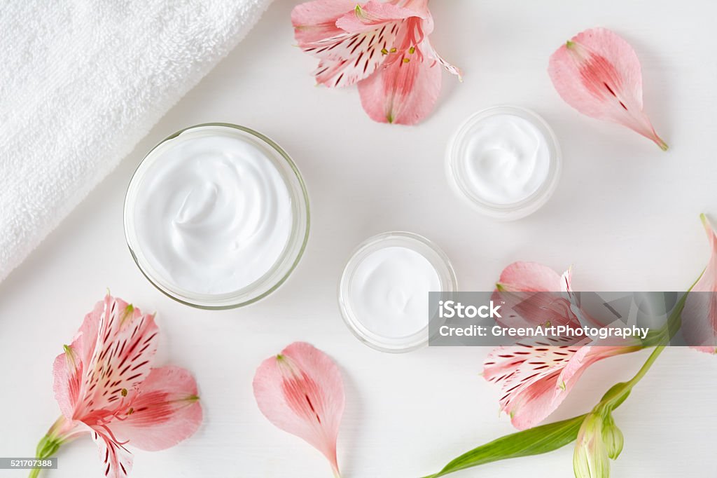 Herbal spa cosmetic cream with pink flowers hygienic skincare lotion Herbal spa cosmetic cream with pink flowers hygienic skincare lotion product wellness and relaxation makeup mask in glass jar with towel on white background Moisturizer Stock Photo