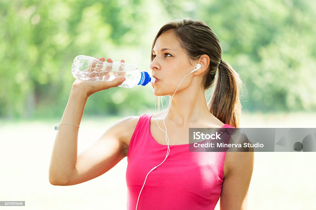 Active woman drinking water Woman drinking water while doing fitness in a park Activity Stock Photo