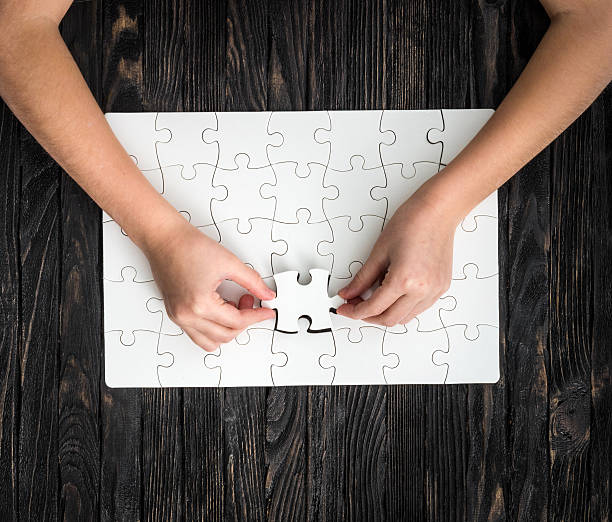 istock hands completing wthite puzzle with the last piece 521708412