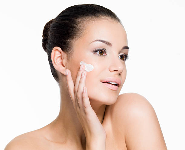 istock Beautiful woman applying cream on face 521708578