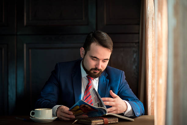 istock young businessman in a cafe reading  magazine 521710158