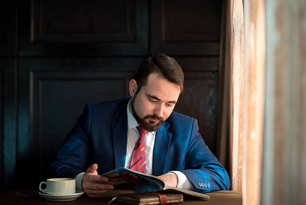 istock young businessman in a cafe reading  magazine 521710350