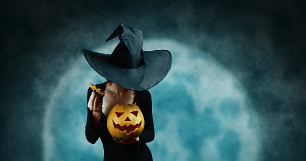 istock Mystery witch opening Halloween carved pumpkin 521710577