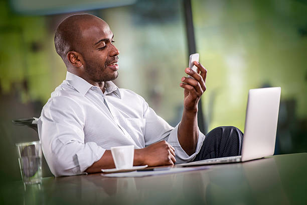 Young African American businessman having a video call on a mobile phone in his office.