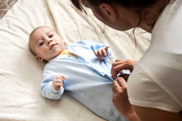 Mother is changing her baby's clothes stock photo