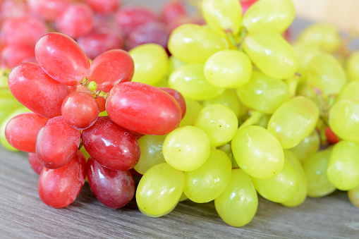 green and red natural grapes on a wooden plate