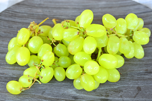 green natural grapes on a wooden plate