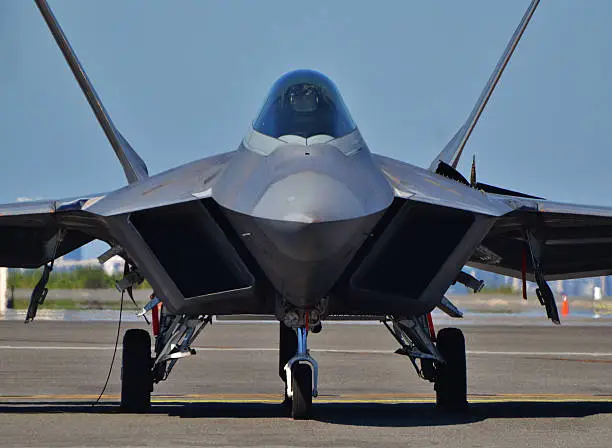 Head-on view of an F-22 fighter jet taxiing down the runway.