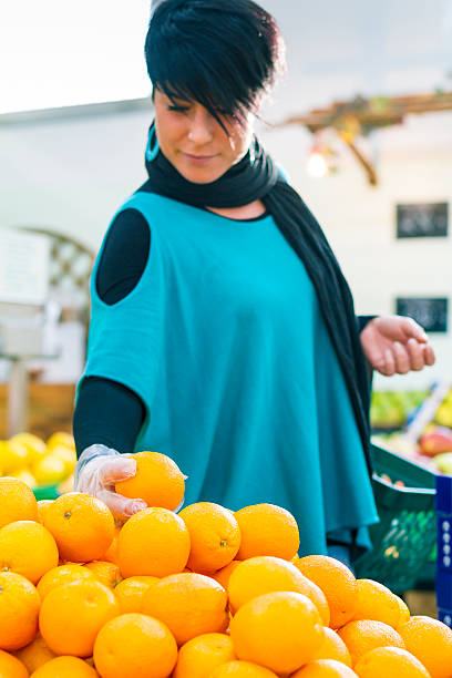 istock Young woman choosing oranges 521743075