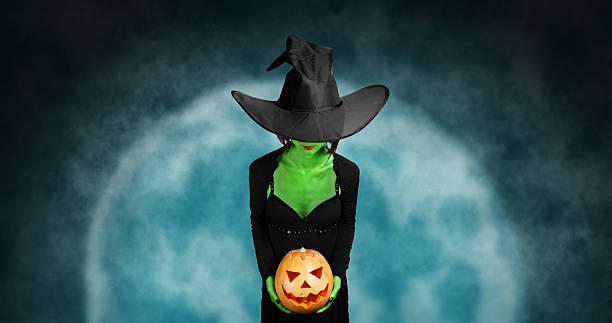 istock Green witch holds Halloween pumpkin 521743589