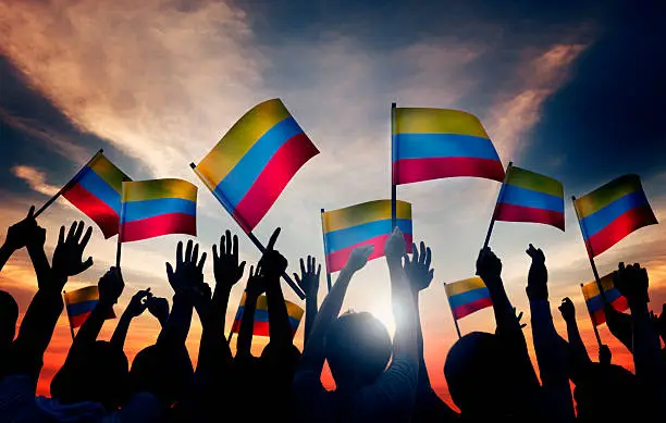 Photo of Group of People Waving Columbian Flags in Back Lit