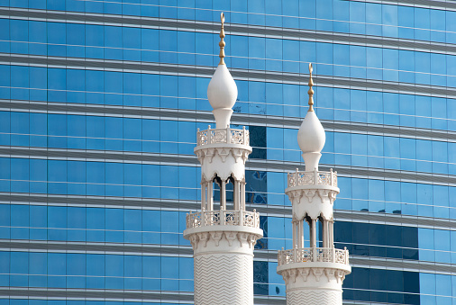Mosque against a glass facade of a modern office building.