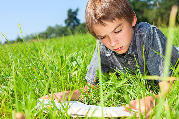 istock Child reading book outdoor 521756947
