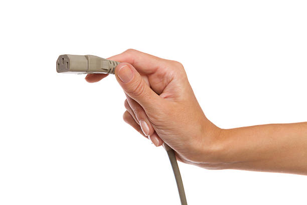 istock Gray IEC 3 pin power supply plug in female hand 521771867