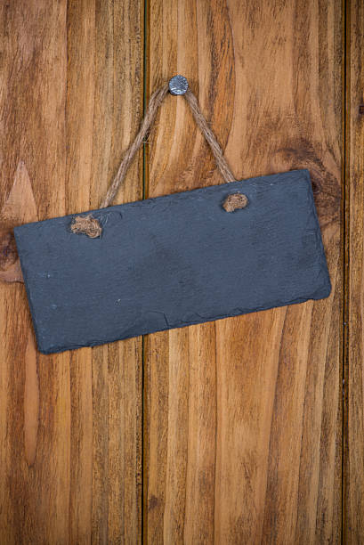 istock Stone signboard with rope hanging on wooden background 521776579