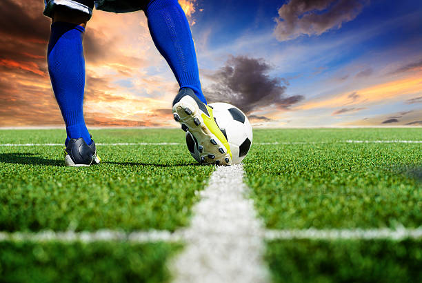 Soccer players practicing by kicking the ball.   