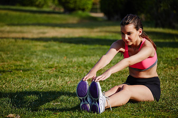 istock Attractive femaqle runner doing stretching legs exercise seated in park 521788639