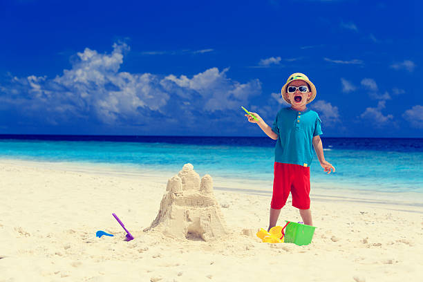 istock happy little boy with built sandcastle on beach 521791107